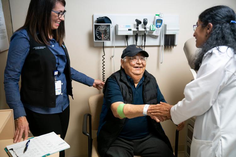 JPS Health Network interpreter Dianna Rodriguez (L) shares with patient Jesus Villalobos the results of his examination by Dr. Kalyani Narra (R). 